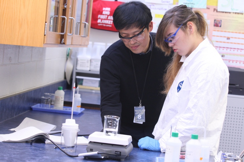 NJ Teaching Fellow Seung Lee works with a student on an AP chemistry lab.